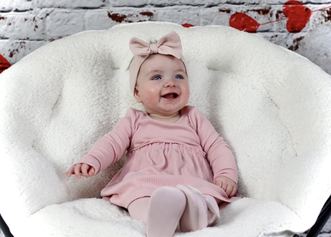 Smiling baby in a soft pink outfit